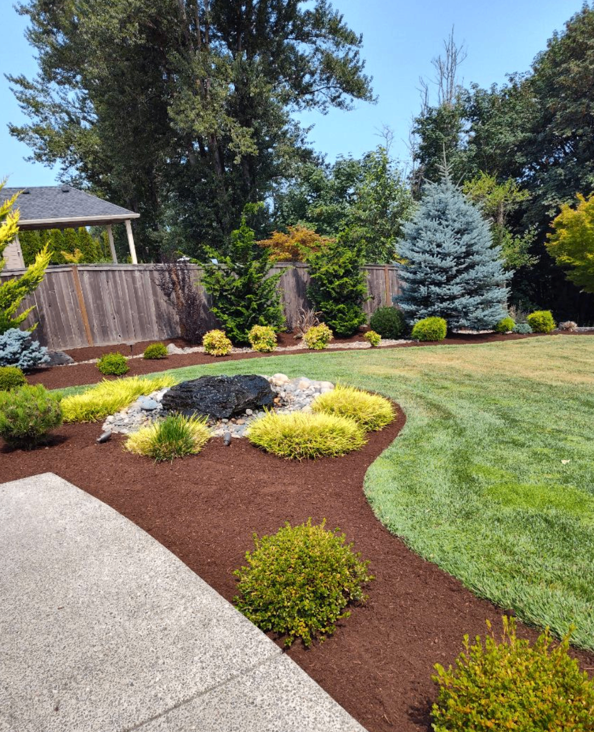 Mulch bed with decorative boulder and striped lawn