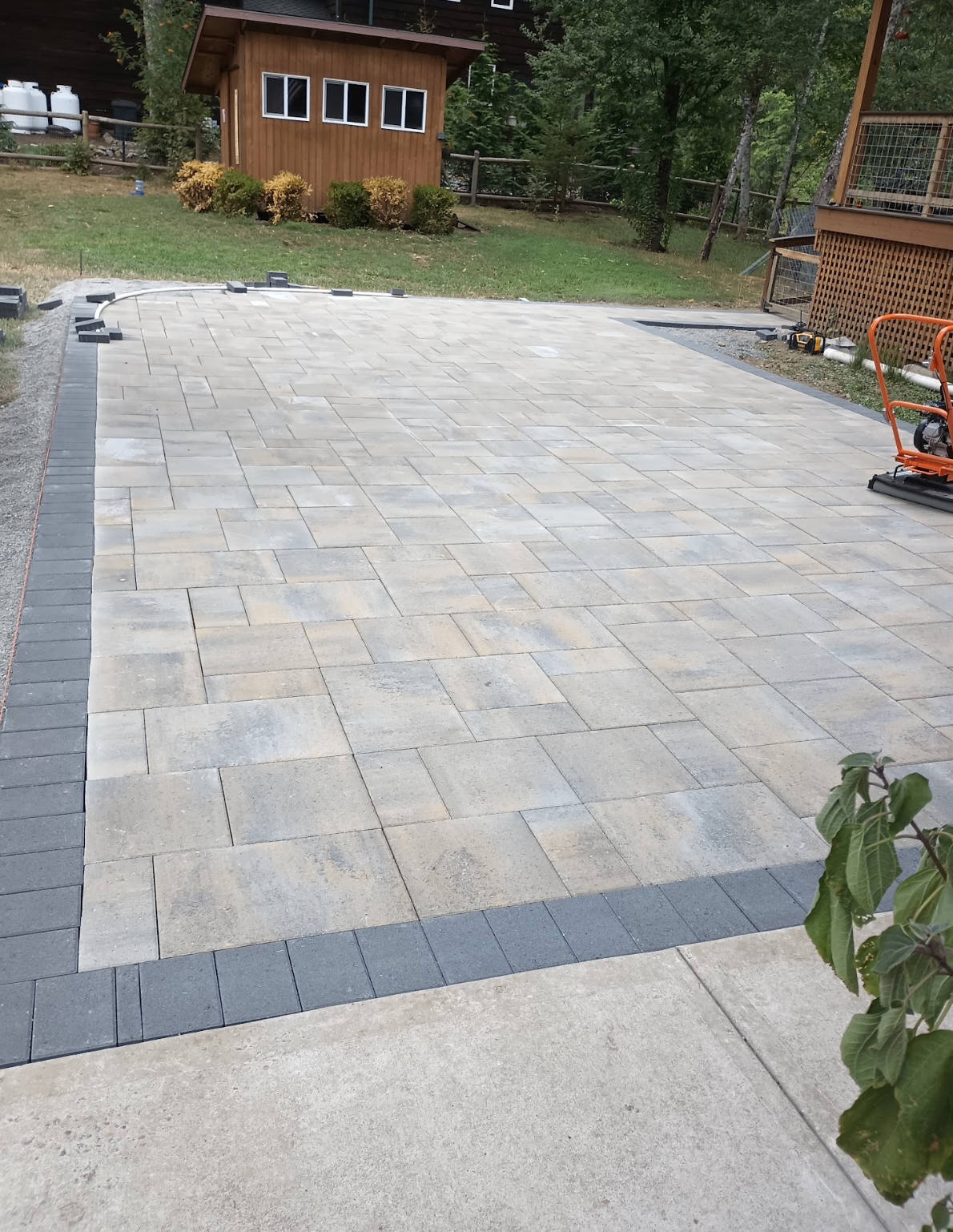 Large rectangular paver patio with dark border course in a backyard
