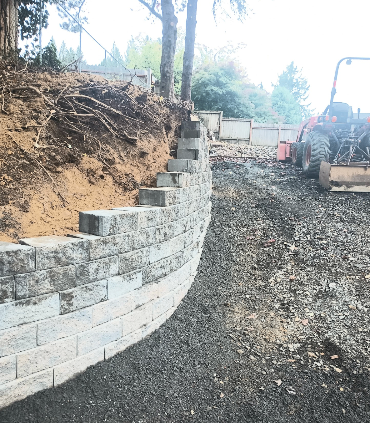 Curved retaining wall under construction with heavy equipment on site