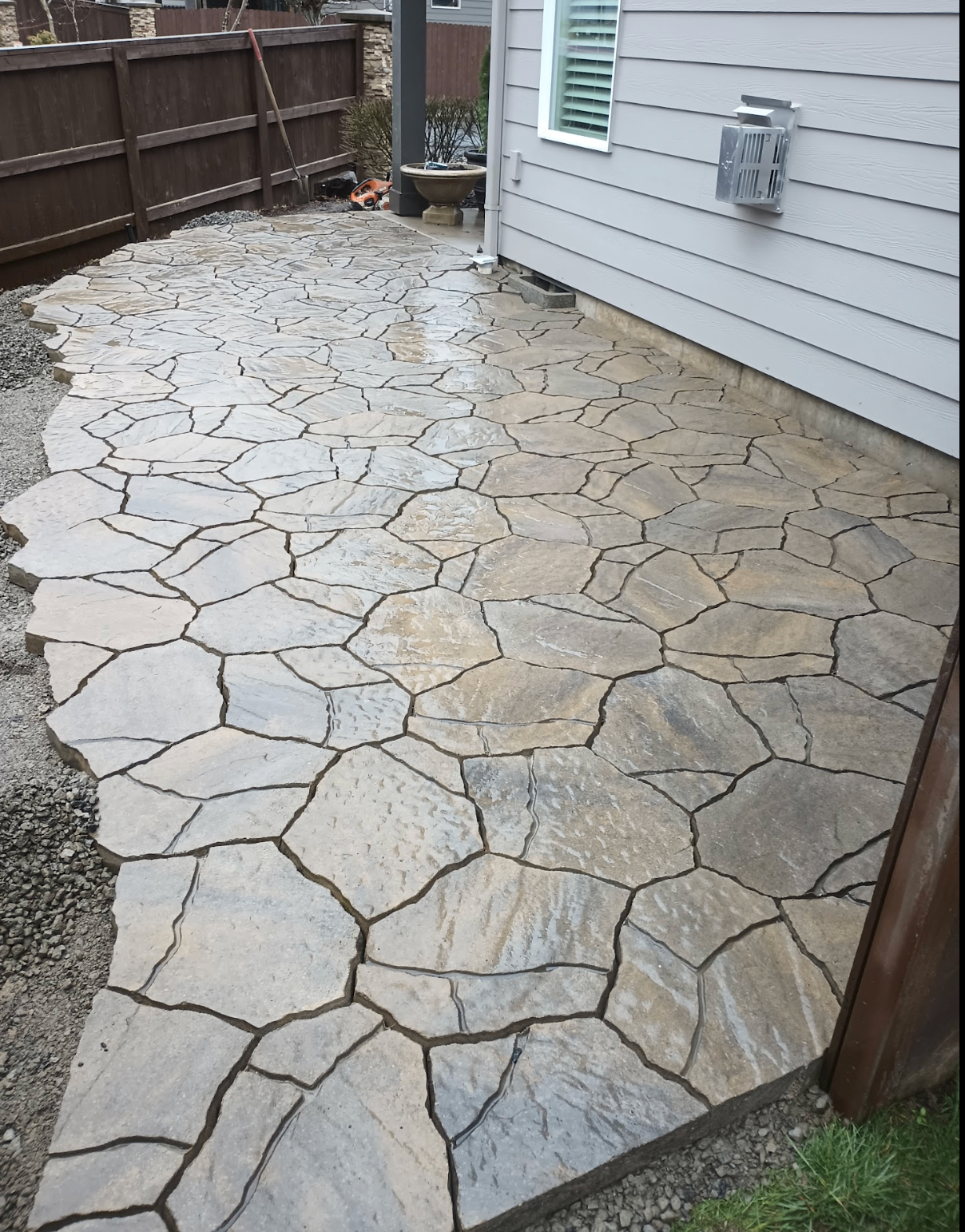 Custom irregular flagstone patio running alongside a house